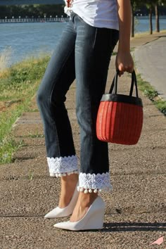 a woman is holding a red and white basket in her hand while standing by the water