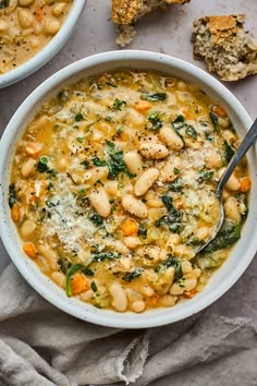 two bowls of white bean soup with spinach, carrots and parmesan cheese