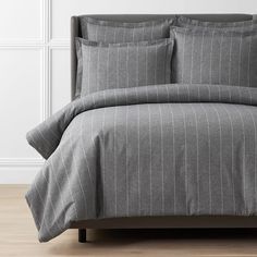 a bed with grey pinstripe comforter and pillows