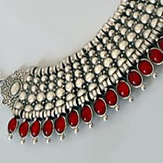 This substantial piece is pure exotic glamour with it's silver-plated collar necklace bordered by polished oval stones. Available in black or red. Festive Silver Jeweled Choker, Red Oxidized Finish Jewelry, Red Oxidized Finish Round Jewelry, Silver Necklaces With Stones For Festive Occasions, Silver Necklace With Stones For Festive Occasions, Bohemian Necklace For Formal Occasions, Red Metal Necklaces With Jewels, Silver Choker With Stones, Silver Stone Choker Jewelry