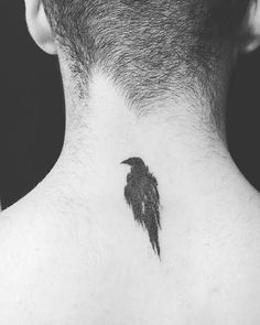 a black bird tattoo on the back of a man's neck