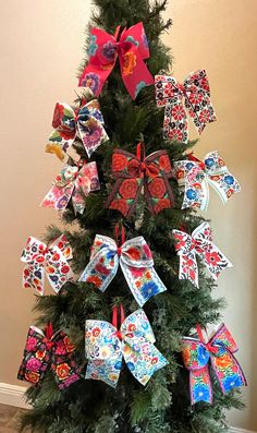 a decorated christmas tree with colorful bows on it's top and decorations hanging from the branches