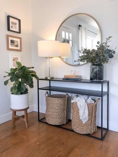 a mirror and some baskets on a table with a lamp in the corner next to it