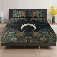 a bed covered in a black and green comforter with an image of the moon on it