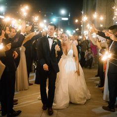 a bride and groom walk through sparklers at their wedding