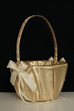 a gold basket with a white bow on it's handle and ribbon around the bottom