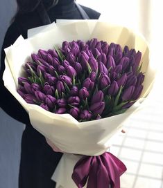 a woman holding a bouquet of purple tulips