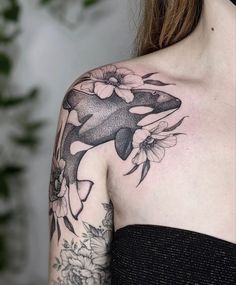 a woman's shoulder with an orca whale and flowers on it