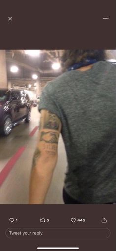 a man with a tattoo on his arm riding a skateboard in a parking garage