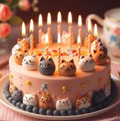 a birthday cake with many cats on it and candles in the shape of kittens