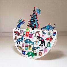 a christmas tree decorated with dinosaurs and other holiday decorations is in the shape of a boat