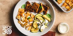 a white plate topped with potatoes and cucumbers next to a container of ranch dressing