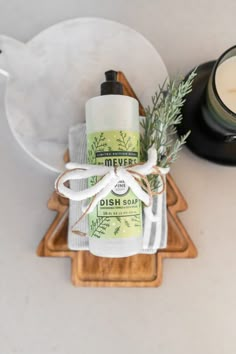 a dish towel and soap sitting on top of a wooden tray next to a candle