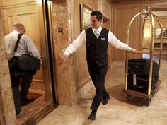 a man in a suit and tie is walking through an elevator with luggage on a dolly