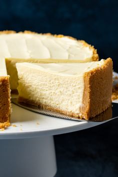 a cheesecake on a white cake plate with one slice cut out and ready to be eaten