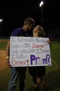 a man and woman kissing while holding a sign