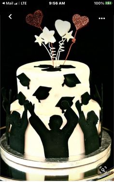 a cake decorated with black and white frosting, topped with silhouettes of people holding balloons