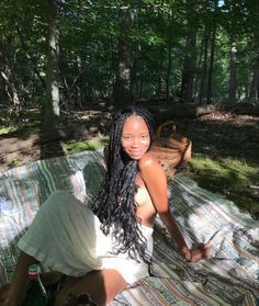 a woman sitting on a blanket in the woods