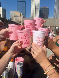 people holding up pink cups in front of each other