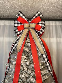 a white christmas tree with red and black ribbon