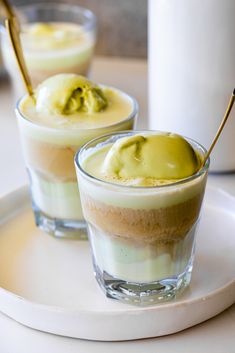 two desserts on a white plate with spoons in each cup and one is filled with ice cream