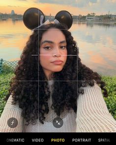 a woman with long curly hair and mickey ears on her head is looking at the camera