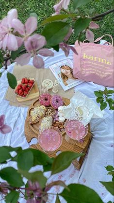 an assortment of pastries on a picnic blanket with pink flowers in the foreground