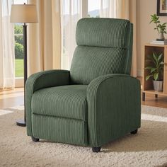 a green recliner chair sitting on top of a rug in front of a window