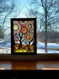 a stained glass window with a tree in the middle and snow on the ground behind it