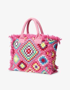 a pink handbag with colorful beads and fringes on the handles, in front of a white background