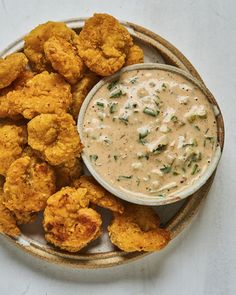 a plate with some fried food on it and a bowl of dip in the middle