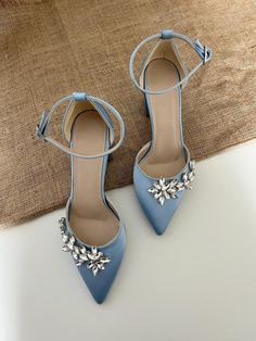 a pair of blue high heeled shoes with flowers on the toe and ankle straps