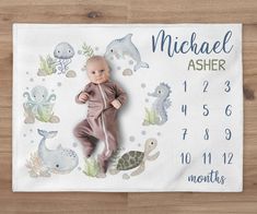 a baby is laying on top of a calendar with sea animals and dolphins around it