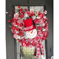 a snowman wreath with candy canes and candies on the front door for christmas