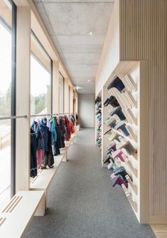 there is a long hallway with many shoes on the shelves and clothes hanging up against the wall