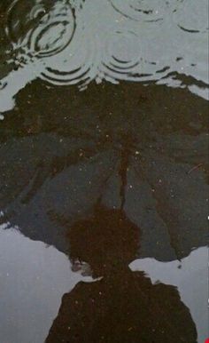 an umbrella is reflected in the water with its reflection on the wet ground and it appears to be upside down