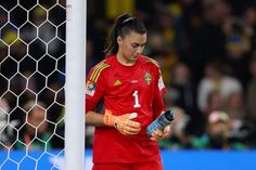 a female soccer player holding a water bottle next to the goalie's net