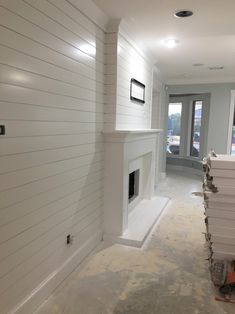 an empty room with white walls and a fireplace in the middle is being built into the wall