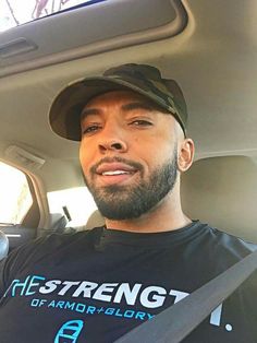 a man sitting in the back seat of a car wearing a black shirt and hat