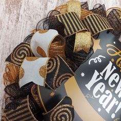 a black and gold new year's wreath on a wooden floor with the words happy new year written on it