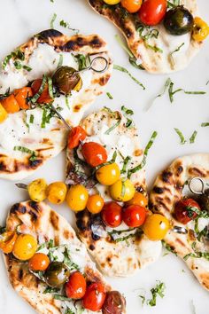 several small pizzas with different types of toppings on top of them, sitting on a white surface