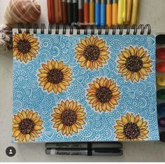 a notebook with sunflowers on it next to crayons and markers