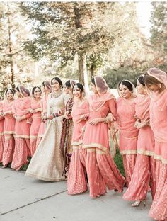 a group of women standing next to each other wearing pink dresses and veils on their heads