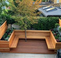 a wooden bench sitting next to a tree in a yard with lots of greenery