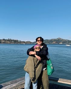 two people hugging each other by the water