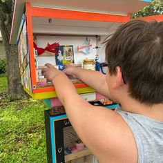 a young boy is playing with an old fashioned toy vending machine in the yard