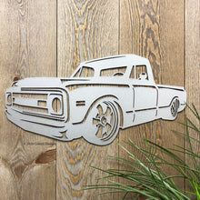 a paper cutout of a classic car on a wooden wall next to a potted plant