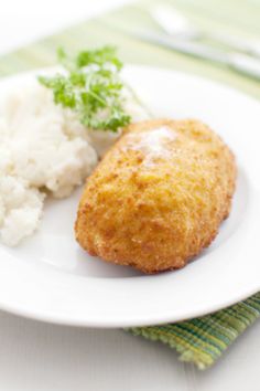 two fried food items in a white bowl on a table with some green sprigs