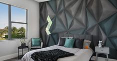 a bedroom with a large bed and two chairs in front of a wall that has geometric designs on it