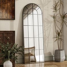 a large mirror sitting on top of a wooden floor next to a potted plant